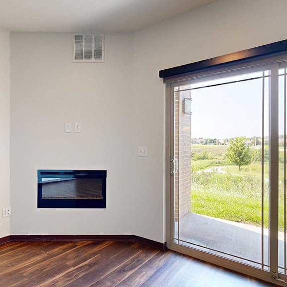 Thumbnail 18 of 29 A living room with hardwood flooring, an electric fireplace, and a sliding glass door to a patio.