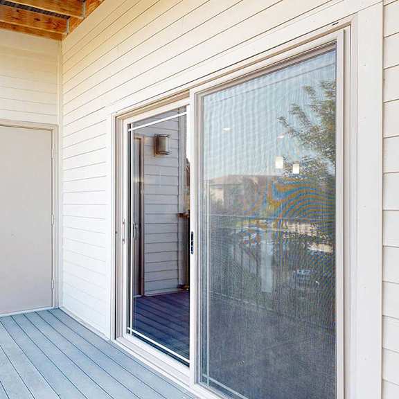 Thumbnail 21 of 34 A balcony with a metal railing, a sliding glass door to the living room, and an outdoor storage closet.