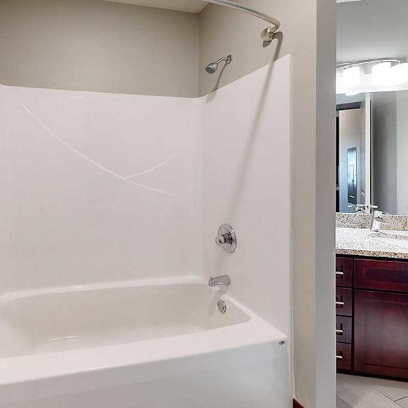 Thumbnail 31 of 34 A white tub shower with a curved curtain rod, and a towel bar.