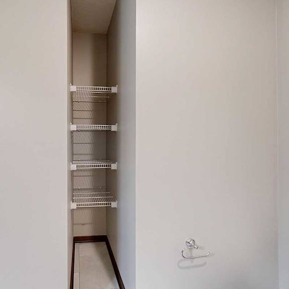 Thumbnail 32 of 34 A bathroom with an inlet with built-in shelves for linen storage.