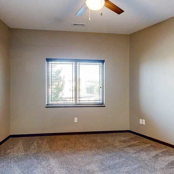 Thumbnail 25 of 34 A carpeted bedroom with a large window and a ceiling fan.