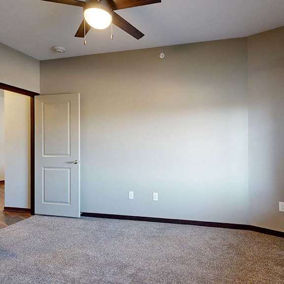 Thumbnail 24 of 34 A carpeted bedroom with a ceiling fan and a door open to a hallway.
