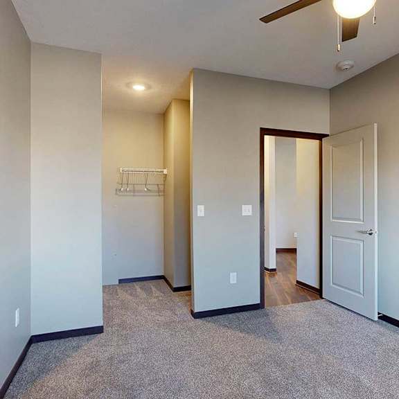 Thumbnail 27 of 34 A carpeted bedroom with a ceiling fan and a spacious walk-in closet.