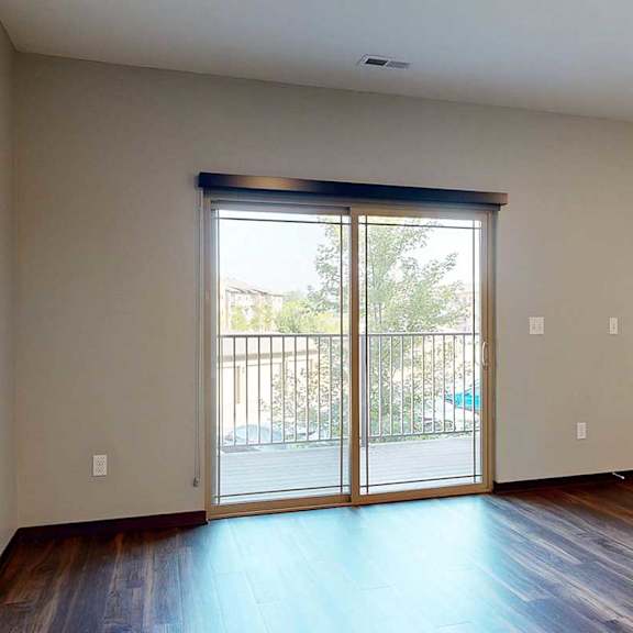 Thumbnail 19 of 34 A living room with a sliding glass door to a balcony with a roller shade.