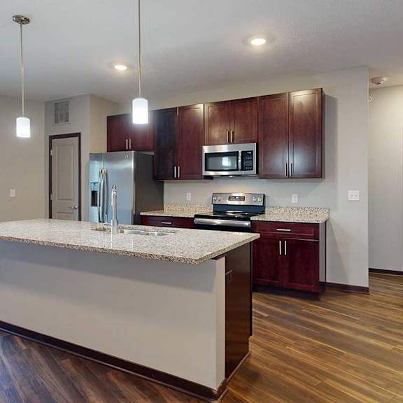 Thumbnail 12 of 34 A modern kitchen with wooden cabinets, granite counters, a large central island, a pantry, and stainless steel appliances.