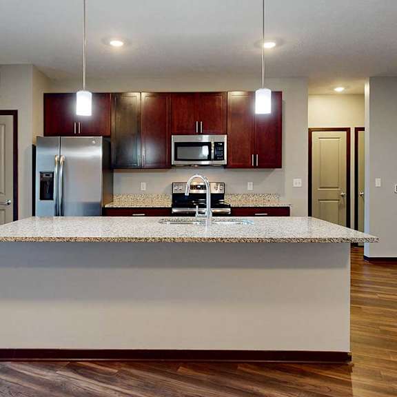 Thumbnail 15 of 34 A modern kitchen with a large central island and pendant lighting.