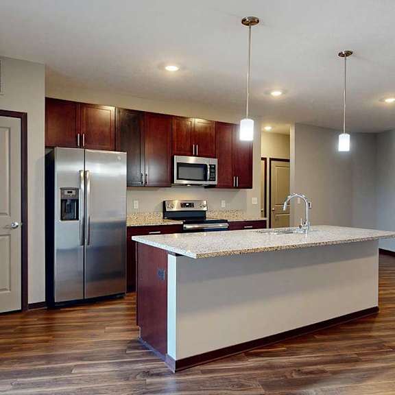 Thumbnail 16 of 34 A modern kitchen with wooden cabinets, granite counters, a large central island, a pantry, and stainless steel appliances.