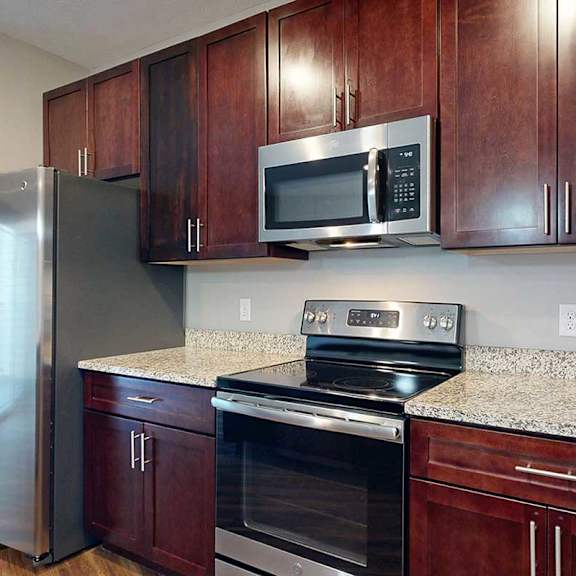 Thumbnail 13 of 34 A close up on a kitchen with brown cabinets, granite counters, and stainless steel appliances.