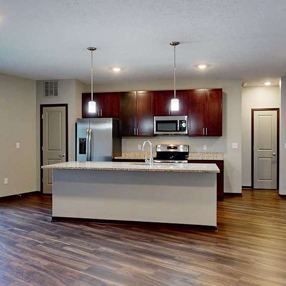 Thumbnail 14 of 34 A modern kitchen with wooden cabinets, granite counters, a large central island, a pantry, and stainless steel appliances.