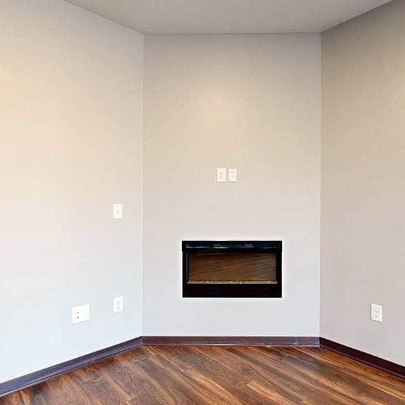 Thumbnail 7 of 34 A living room with an electric fireplace and hardwood flooring.