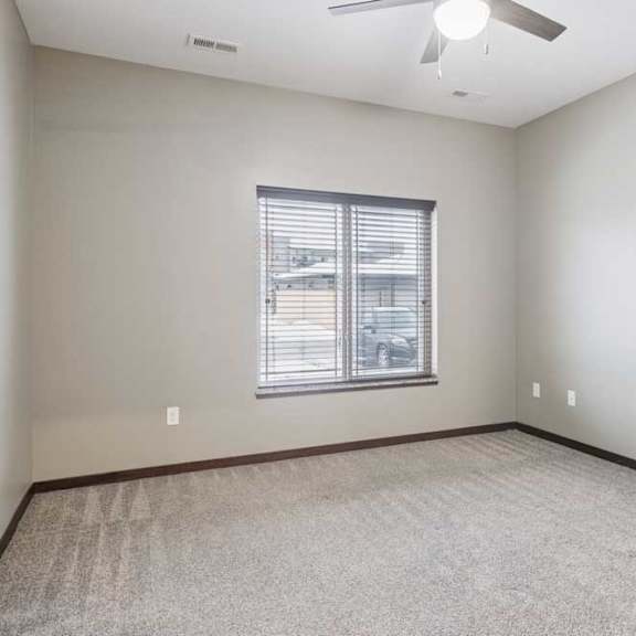Thumbnail 12 of 15 A carpeted bedroom with a ceiling fan and a window.