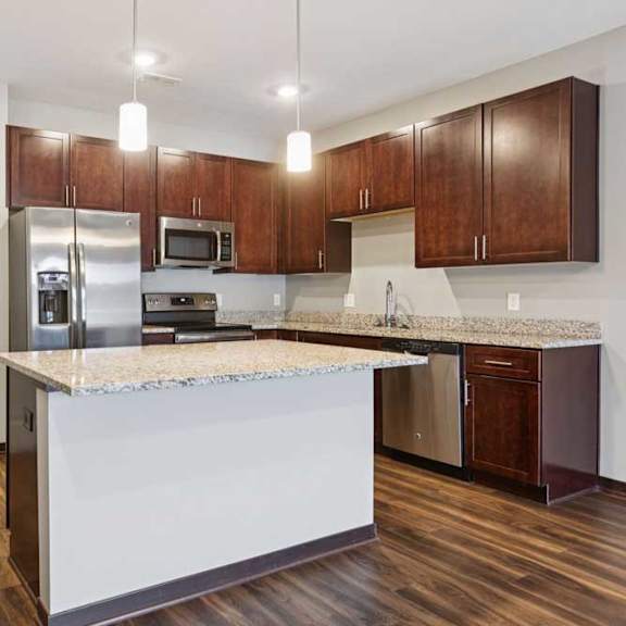 Thumbnail 4 of 15 A kitchen with dark wood cabinets, granite countertops, and stainless steel appliances.
