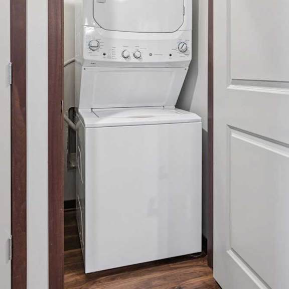 Thumbnail 15 of 15 A stacked full-sized washer and dryer in a laundry room.