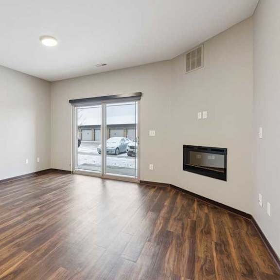 Thumbnail 8 of 15 A living room with hardwood-style flooring, an electric fireplace, and a sliding glass door to a patio.