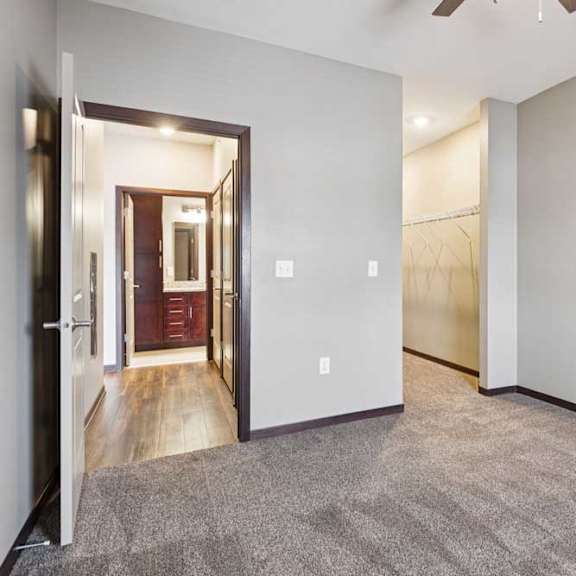 Thumbnail 13 of 18 A carpeted bedroom with a ceiling fan and an open walk-in closet.