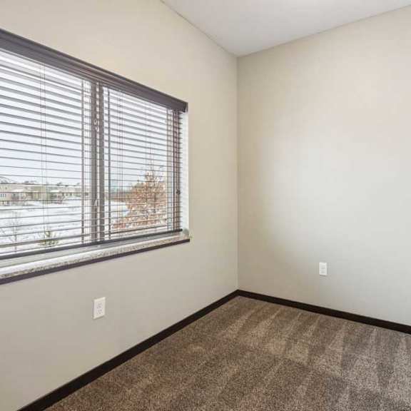 Thumbnail 9 of 18 A carpeted den space with a large window and several outlets.