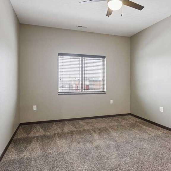 Thumbnail 28 of 34 A carpeted bedroom with a ceiling fan and a window.