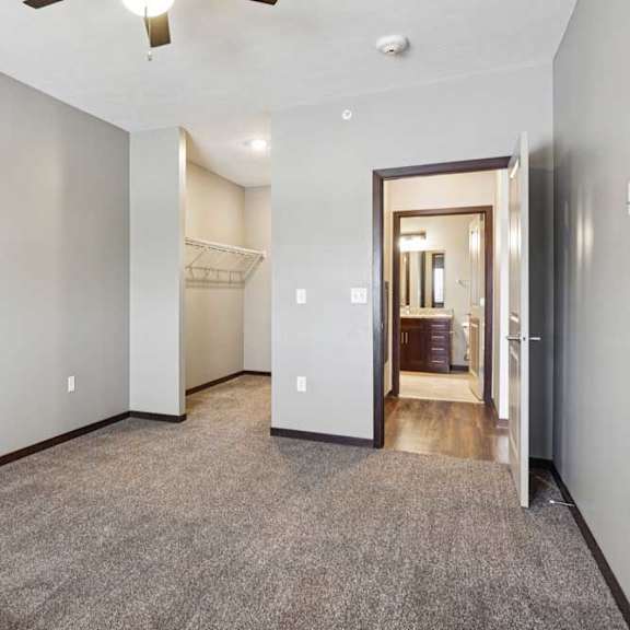 Thumbnail 27 of 34 A carpeted bedroom with a ceiling fan and an open walk-in closet.