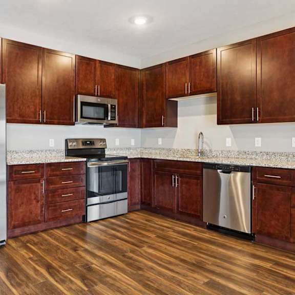 Thumbnail 21 of 34 A kitchen with dark wood cabinets, granite countertops, and stainless steel appliances.