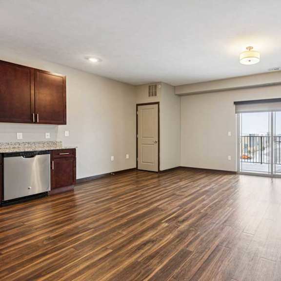 Thumbnail 23 of 34 A living room with hardwood-style flooring and a sliding glass door to a balcony.