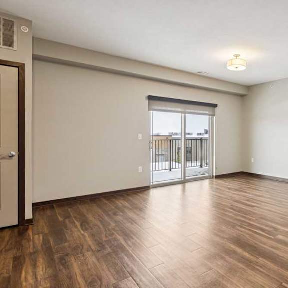 Thumbnail 24 of 34 A living room with hardwood-style flooring and a sliding glass door to a balcony