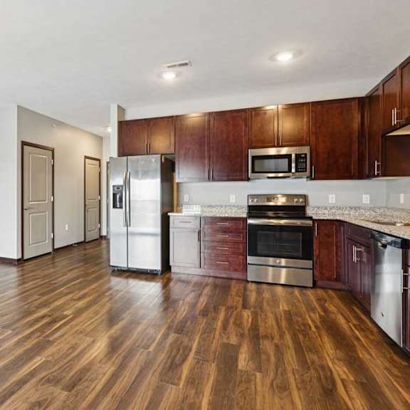 Thumbnail 26 of 34 A kitchen with dark wood cabinets, granite countertops, and stainless steel appliances.