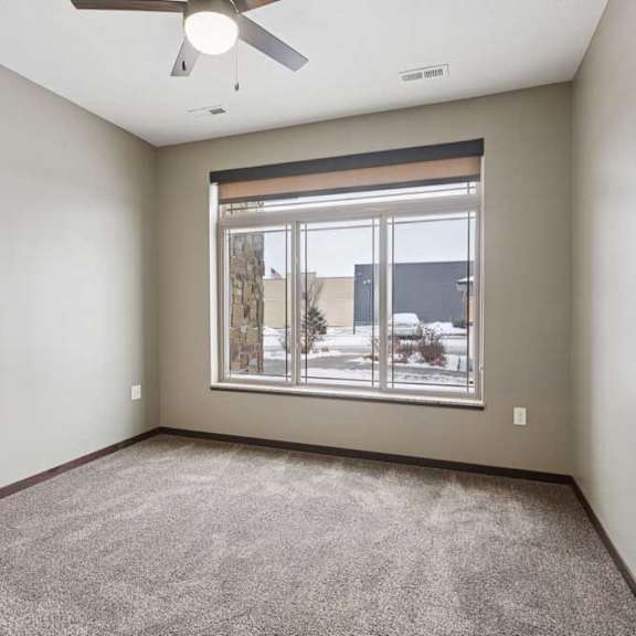 Thumbnail 20 of 23 A carpeted bedroom with a ceiling fan and a floor-to-ceiling window.