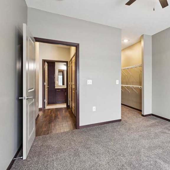 Thumbnail 19 of 23 A carpeted bedroom with a ceiling fan and an open walk-in closet.