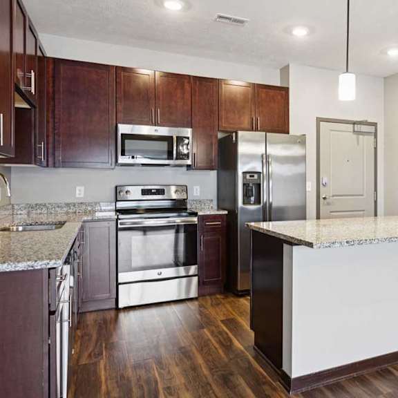 Thumbnail 14 of 23 A kitchen with dark wood cabinets, granite countertops, and stainless steel appliances.
