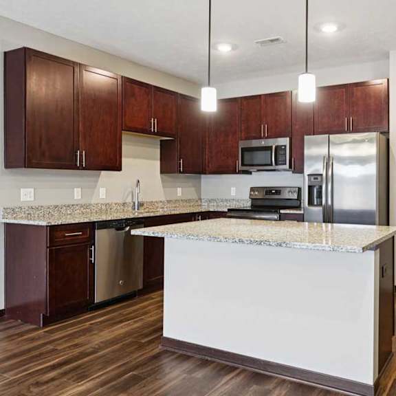 Thumbnail 15 of 23 A kitchen with dark wood cabinets, granite countertops, and stainless steel appliances.