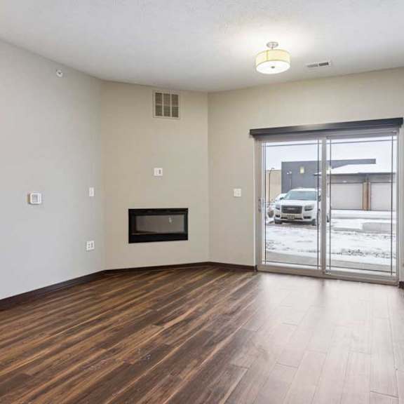 Thumbnail 17 of 23 A living room with hardwood-style flooring, an electric fireplace, and a sliding glass door to a patio.