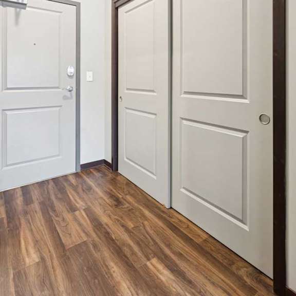 Thumbnail 4 of 11 A hallway with a double-door closet and the front door at the end.