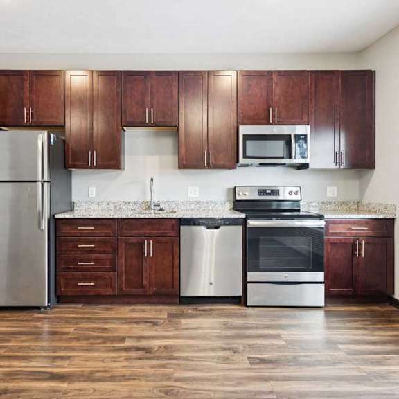 Thumbnail 6 of 11 A kitchen with dark wood cabinets, granite countertops, and stainless steel appliances.
