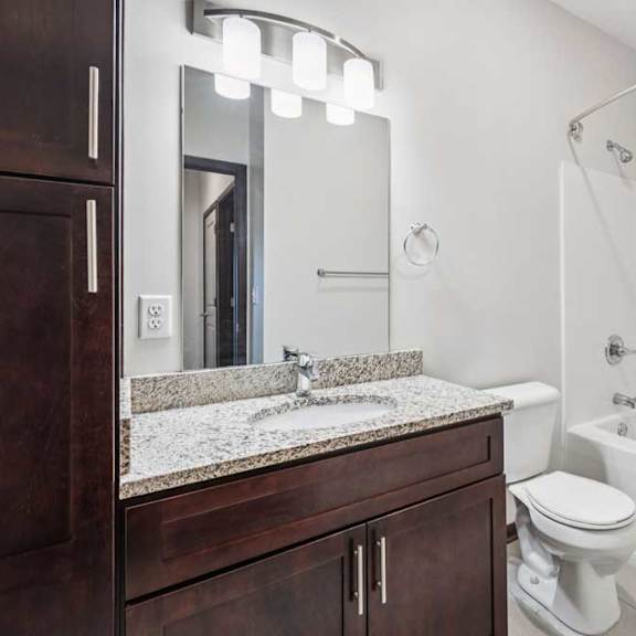 Thumbnail 21 of 21 A bathroom with a granite vanity, dark wooden cabinets, and a tub shower.