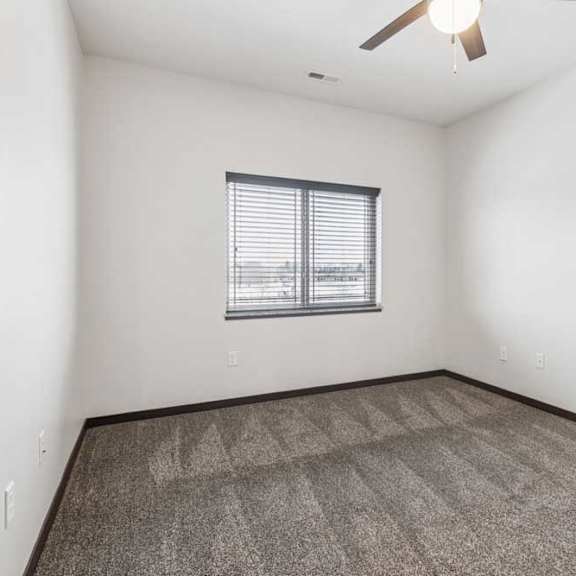 Thumbnail 12 of 21 A carpeted bedroom with a ceiling fan and a window.