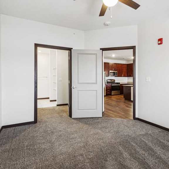Thumbnail 11 of 21 A carpeted bedroom with a ceiling fan and an open walk-in closet.