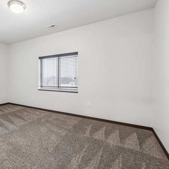 Thumbnail 19 of 21 A carpeted bedroom with a large window.