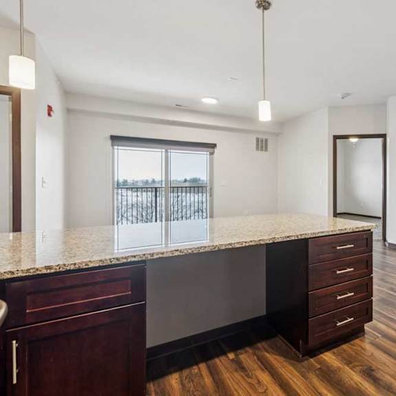 Thumbnail 7 of 21 A kitchen with dark wooden cabinets in front of a spacious living room.