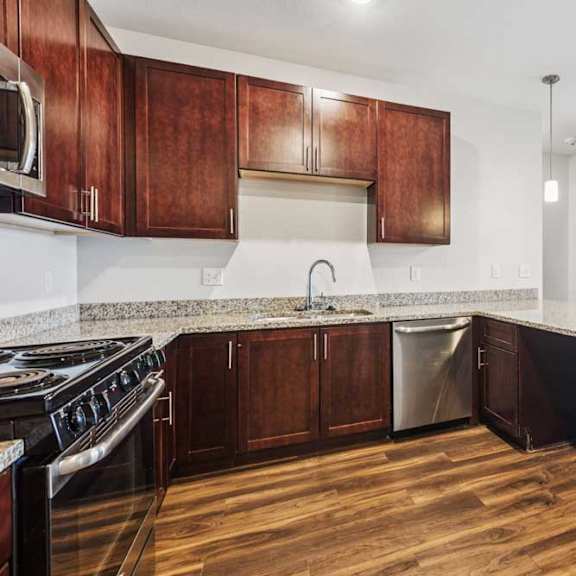 Thumbnail 6 of 21 A kitchen with dark wood cabinets, granite countertops, and stainless steel appliances.