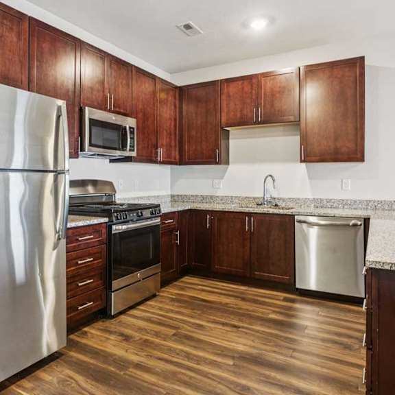 Thumbnail 4 of 21 A kitchen with dark wood cabinets, granite countertops, and stainless steel appliances.