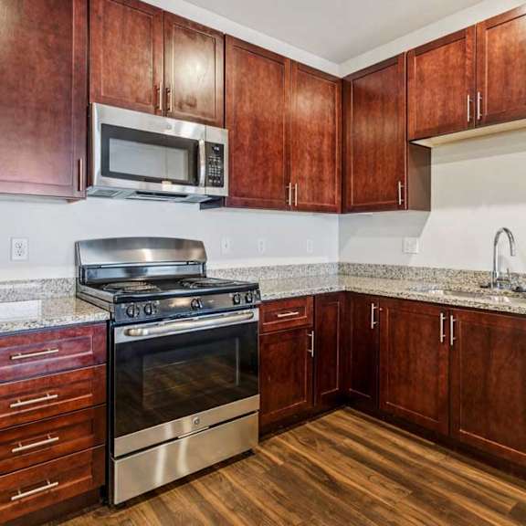 Thumbnail 5 of 21 A kitchen with dark wood cabinets, granite countertops, and stainless steel appliances.
