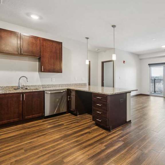 Thumbnail 8 of 21 A large kitchen peninsula in front of a spacious living room and dining area.