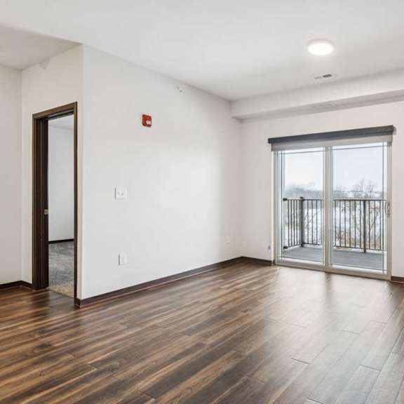 Thumbnail 9 of 21 A living room with hardwood-style flooring and a sliding glass door to a patio.