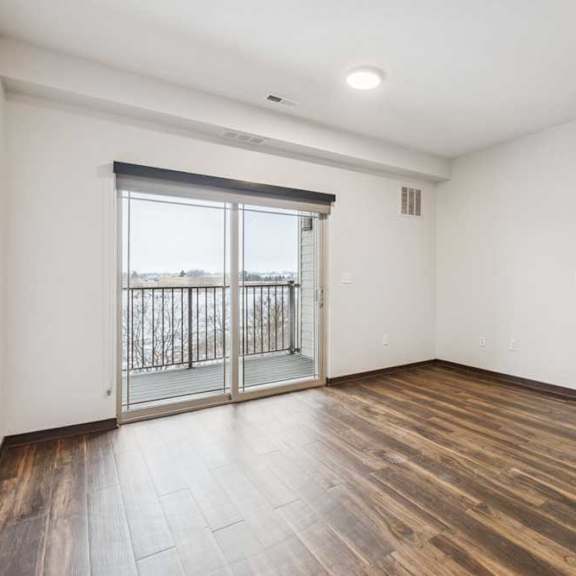 Thumbnail 10 of 21 A living room with hardwood-style flooring and a sliding glass door to a patio.