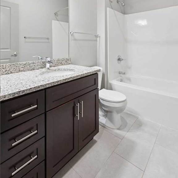 Thumbnail 19 of 19 A bathroom with a granite vanity, dark wooden cabinets, and a tub shower.