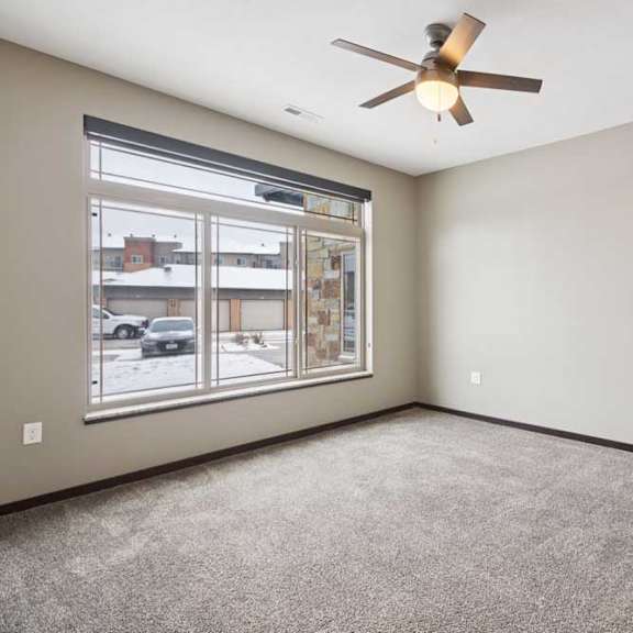 Thumbnail 12 of 19 A carpeted bedroom with a ceiling fan and a floor-to-ceiling window.