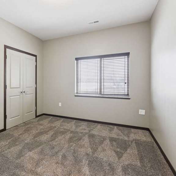 Thumbnail 17 of 19 A carpeted bedroom with two double-door closets, and an oversized window.