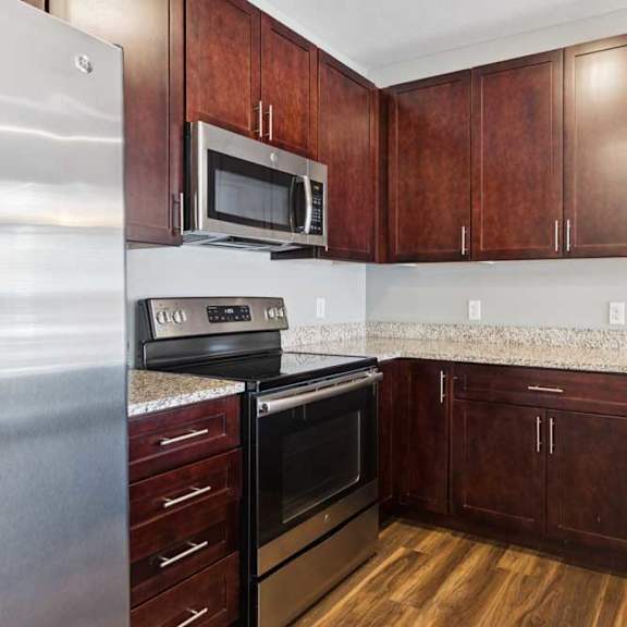 Thumbnail 5 of 19 A kitchen with dark wood cabinets, granite countertops, and stainless steel appliances.