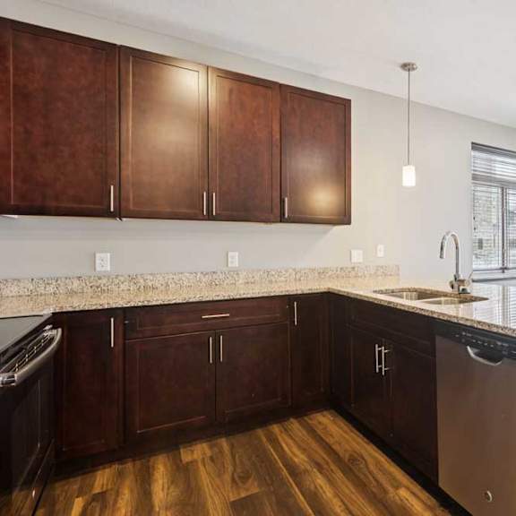 Thumbnail 6 of 19 A kitchen with dark wood cabinets, granite countertops, stainless steel appliances, and a peninsula in front of a dining room..