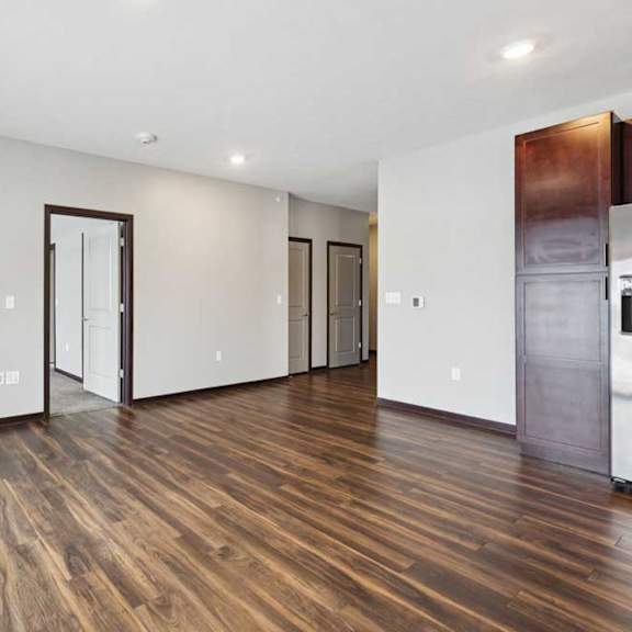 Thumbnail 10 of 19 A spacious living room with hardwood-style flooring and an electric fireplace.